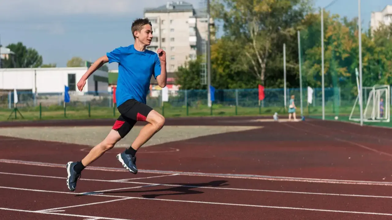 Młody biegacz na bieżni podczas zajęć sportowych dla młodzieży.
