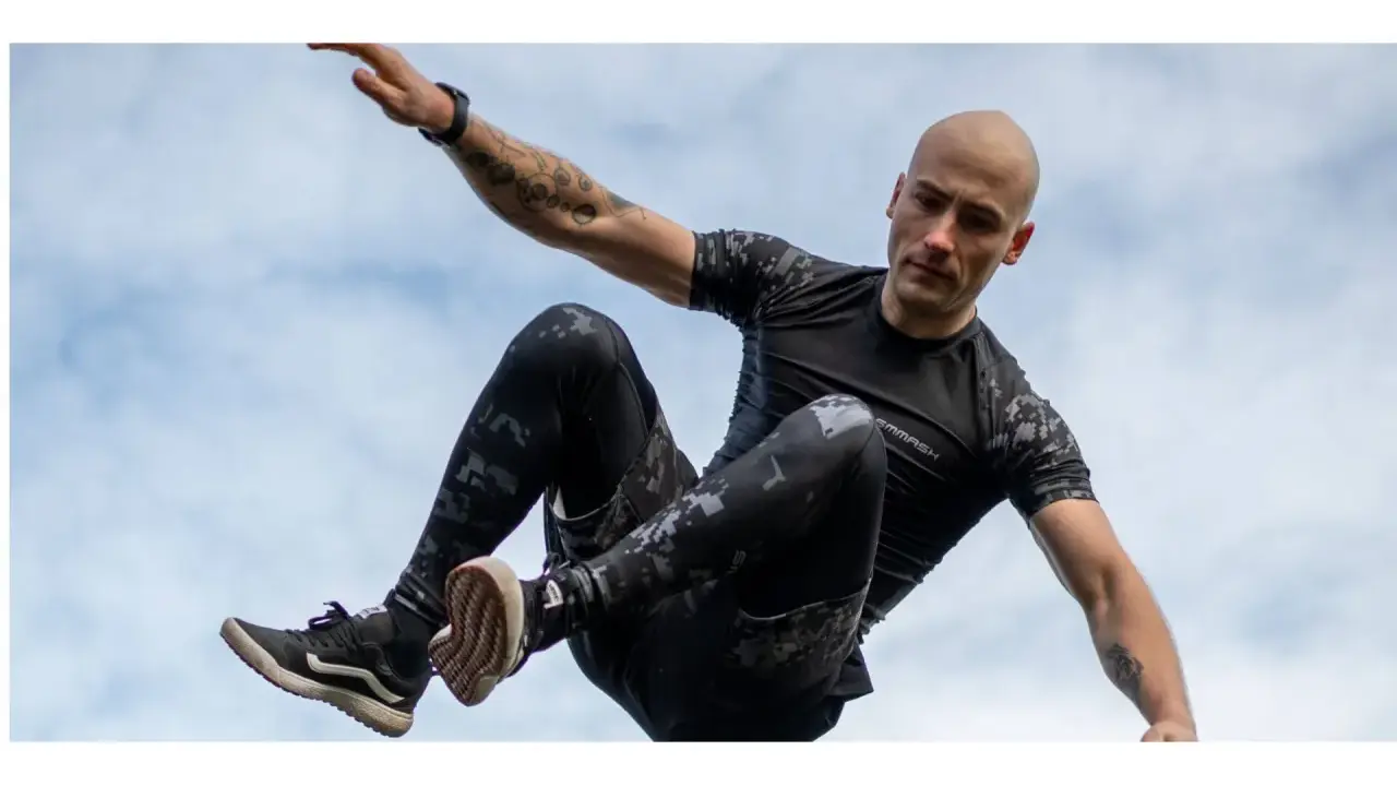 Mężczyzna w ruchu, jakby ćwiczył hiit. Co to za trening? Dynamiczne skoki i akrobacje na tle nieba.