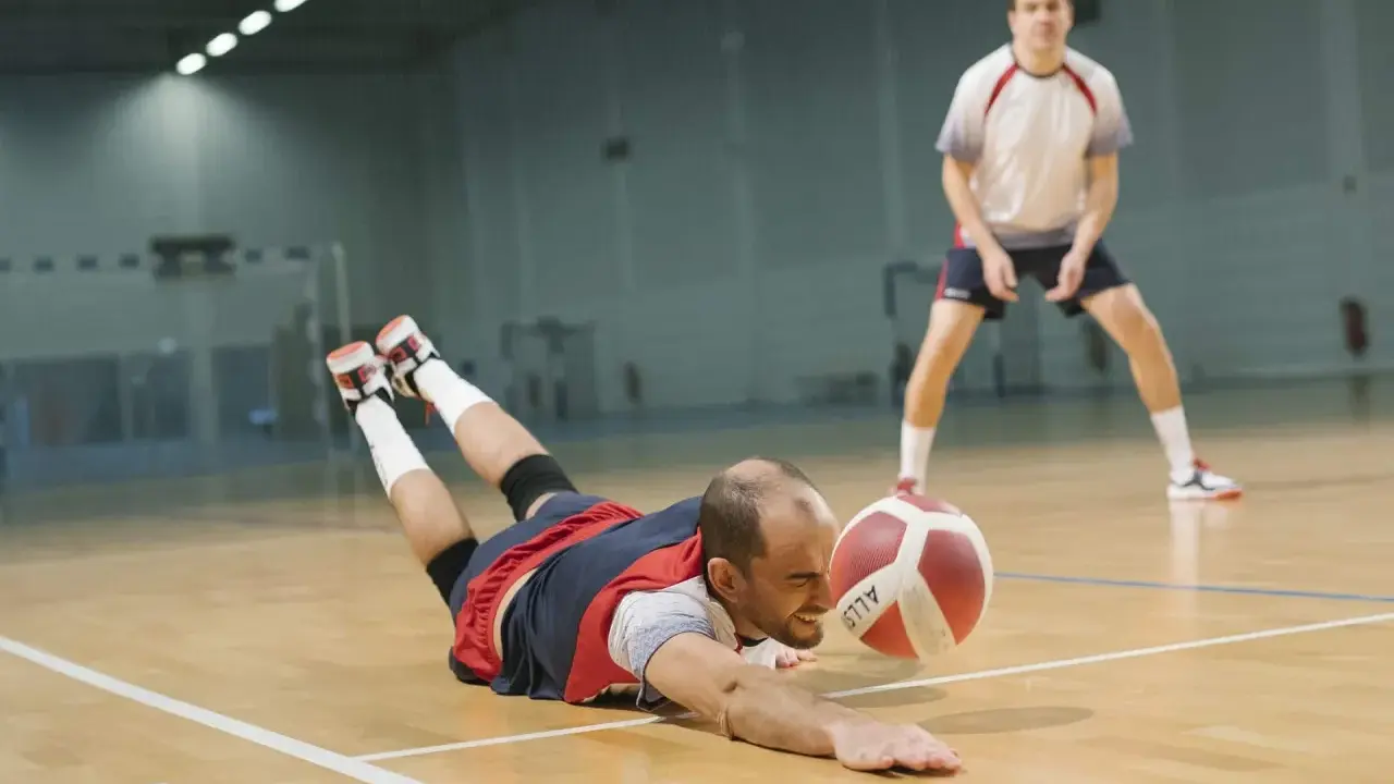 Libero w siatkówce wykonuje efektowną obronę, rzucając się na parkiet, by ratować piłkę.