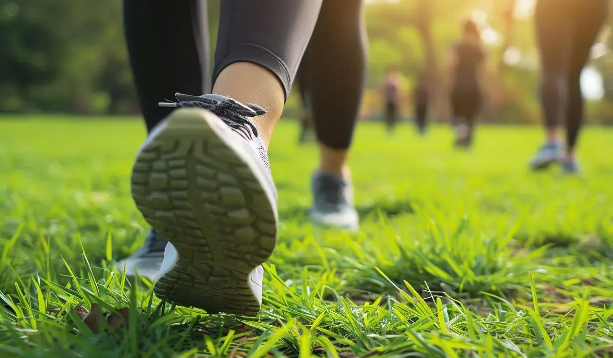 Ludzie uprawiający power walking na trawie w parku, w promieniach słońca.