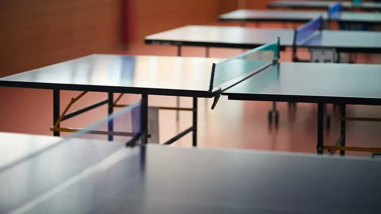 Rzędy stołów do ping ponga czekają na graczy. Sieć do ping ponga jest napięta, gotowa na emocjonującą grę.