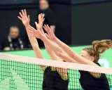 Dwie siatkarki wykonują blok w siatkówce, wyciągając ręce nad siatką, by zatrzymać atak przeciwnika.