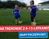 Dwóch chłopców na boisku piłkarskim, każdy z nogą na zielonej piłce. To początek ich treningu piłkarskiego dla dzieci 4-6 lat.