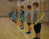 Dzieci z klas 1-3 na lekcji WF ćwiczą z hula-hop. Radosne gry i zabawy sportowe.