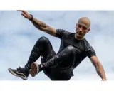 Mężczyzna w ruchu, jakby ćwiczył hiit. Co to za trening? Dynamiczne skoki i akrobacje na tle nieba.