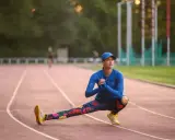 Królowa sportu w kwiecistych legginsach rozciąga się na bieżni.
