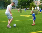 Trening piłki nożnej trwa w najlepsze! Tata uczy córkę dryblingu na zielonej murawie.