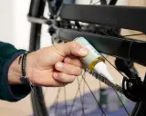 Osoba aplikuje smar na łańcuch rowerowy, dbając o jego płynne działanie. Czyszczenie łańcucha rowerowego to klucz do sprawnej jazdy.