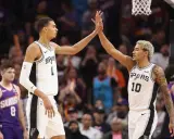 Dwóch koszykarzy San Antonio Spurs świętuje udaną akcję, która zakończyła się asystą w koszykówce.