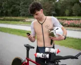 Kolarz sprawdza na telefonie, jaka kadencja na rowerze jest optymalna. Trzyma kask, gotowy do startu.