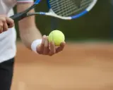 Gracz trzyma piłkę tenisową, gotowy do serwisu. Kluczowy moment decydującego **tenis tie break**.