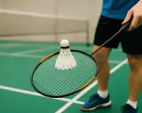 Gracz trzyma rakietę z lotką, gotowy do gry. Poznaj podstawowe badminton zasady, by cieszyć się grą na zielonym korcie.