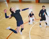 Siatkarze w akcji. Kobieta wyskakuje do ataku, a jej koledzy z drużyny czekają na dalszy rozwój gry. Złoty set siatkówka co to znaczy? To decydująca partia meczu.
