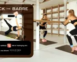 Kobiety wykonują ćwiczenia na macie w sali treningowej. Na ekranie telefonu widać kobietę w pozycji bocznej deski, a obok niej dwie kobiety ćwiczące przy drążku.