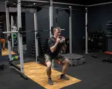 Mężczyzna wykonuje przysiad z kettlebell trzymanym w chwycie nachwyt i podchwyt.