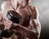 Mężczyzna podnosi ciężarek, jego napięty biceps jest wyraźnie widoczny.