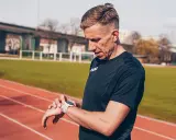 Biegacz sprawdza zegarek na bieżni. Czas na maraton!