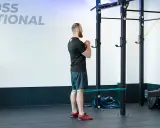 Mężczyzna wykonuje ćwiczenie spanish squat z gumą oporową wokół ud, przygotowując się do przysiadu.