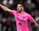 Bramkarz w różowej koszulce Hellas Verona wskazuje palcem, jakby chciał wiedzieć, ile trwa dogrywka w piłce nożnej.