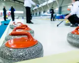 Kamienie do curlingu, każdy ważący ok. 20 kg, czekają na lodzie.