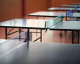 Rzędy stołów do ping ponga czekają na graczy. Sieć do ping ponga jest napięta, gotowa na emocjonującą grę.