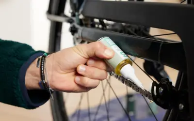 Osoba aplikuje smar na łańcuch rowerowy, dbając o jego płynne działanie. Czyszczenie łańcucha rowerowego to klucz do sprawnej jazdy.