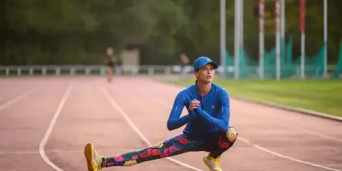 Królowa sportu w kwiecistych legginsach rozciąga się na bieżni.