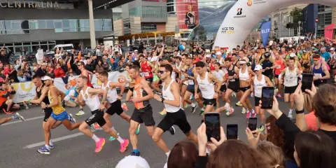 Uczestnicy maratonu w Warszawie, gotowi do startu. To świetny przykład, jak przygotować się do maratonu: trening, determinacja i wsparcie kibiców.