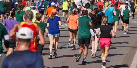Tłum biegaczy pokonuje trasę maratonu. Czy wiesz, ile km ma maraton? To aż 42,195 km!