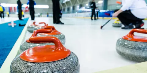 Kamienie do curlingu, każdy ważący ok. 20 kg, czekają na lodzie.