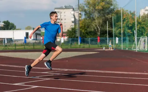 Młody biegacz na bieżni podczas zajęć sportowych dla młodzieży.