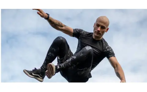 Mężczyzna w ruchu, jakby ćwiczył hiit. Co to za trening? Dynamiczne skoki i akrobacje na tle nieba.