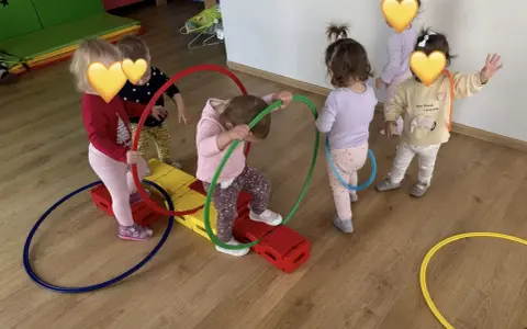Dzieci bawią się kolorowymi hula hop na sali gimnastycznej. Radość i ruch to najlepsze zabawy z hula hop!