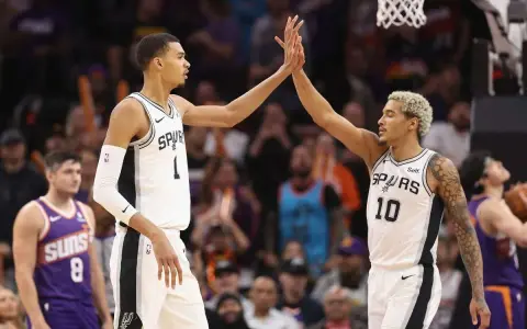 Dwóch koszykarzy San Antonio Spurs świętuje udaną akcję, która zakończyła się asystą w koszykówce.