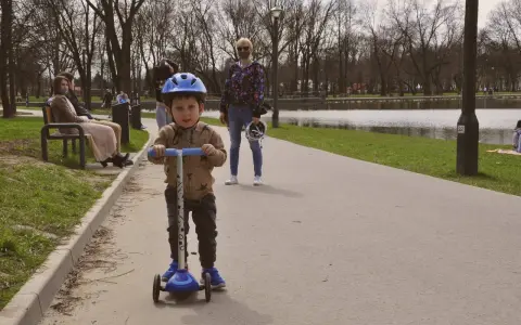 Chłopiec w kasku na hulajnodze cieszy się aktywnymi grami i zabawami na świeżym powietrzu.