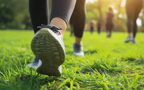 Ludzie uprawiający power walking na trawie w parku, w promieniach słońca.
