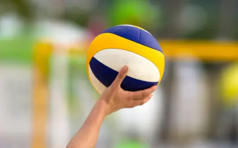 Dłoń trzyma piłkę do siatkówki, gotową do zagrywki. Napięcie przed tie break siatkówka.