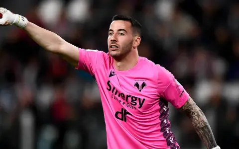 Bramkarz w różowej koszulce Hellas Verona wskazuje palcem, jakby chciał wiedzieć, ile trwa dogrywka w piłce nożnej.