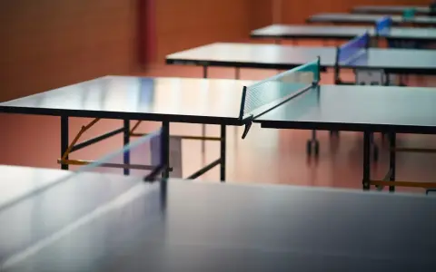 Rzędy stołów do ping ponga czekają na graczy. Sieć do ping ponga jest napięta, gotowa na emocjonującą grę.