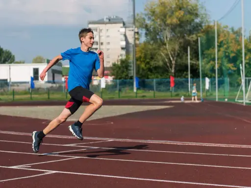 Młody biegacz na bieżni podczas zajęć sportowych dla młodzieży.