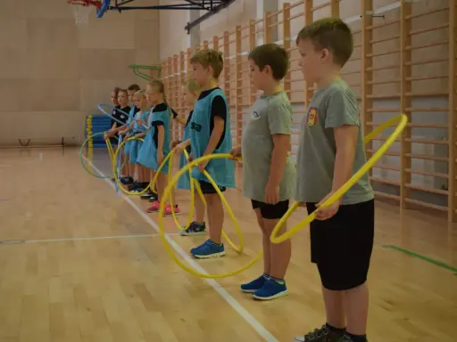 Dzieci z klas 1-3 na lekcji WF ćwiczą z hula-hop. Radosne gry i zabawy sportowe.