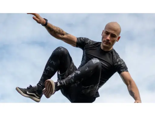 Mężczyzna w ruchu, jakby ćwiczył hiit. Co to za trening? Dynamiczne skoki i akrobacje na tle nieba.