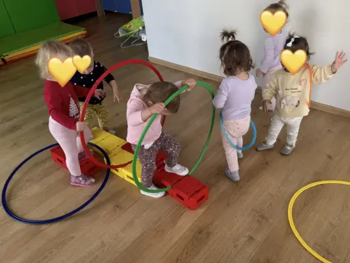 Dzieci bawią się kolorowymi hula hop na sali gimnastycznej. Radość i ruch to najlepsze zabawy z hula hop!