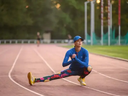 Królowa sportu w kwiecistych legginsach rozciąga się na bieżni.