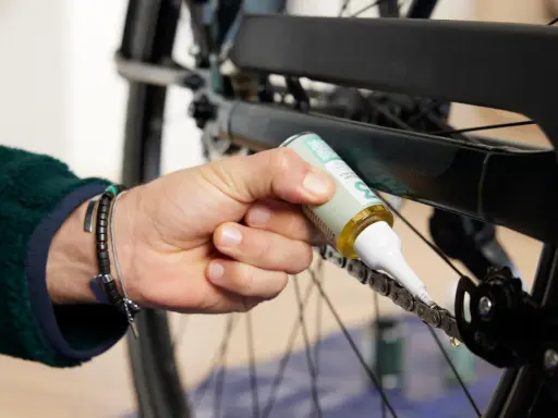 Osoba aplikuje smar na łańcuch rowerowy, dbając o jego płynne działanie. Czyszczenie łańcucha rowerowego to klucz do sprawnej jazdy.