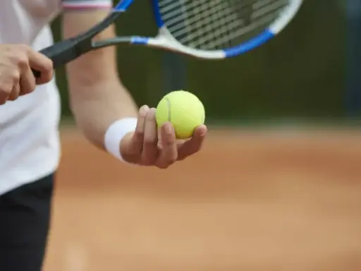 Gracz trzyma piłkę tenisową, gotowy do serwisu. Kluczowy moment decydującego **tenis tie break**.