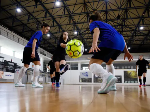 Piłkarki walczą o piłkę na hali. Zastanawiasz się, ile trwa mecz futsalu? To dynamiczna gra, która wymaga szybkości i precyzji.