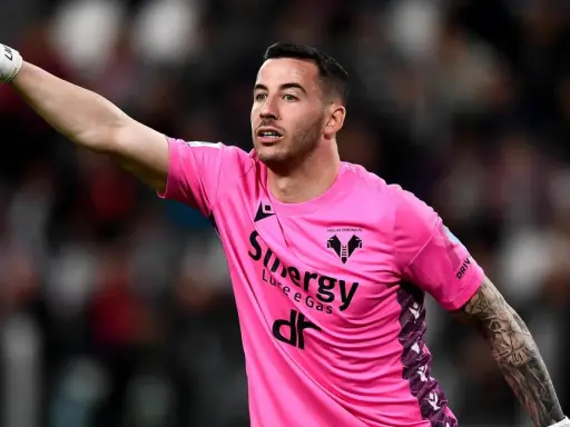 Bramkarz w różowej koszulce Hellas Verona wskazuje palcem, jakby chciał wiedzieć, ile trwa dogrywka w piłce nożnej.