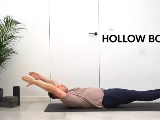 Mężczyzna ćwiczy pozycję hollow body na macie. Ręce wyciągnięte nad głowę, nogi uniesione.