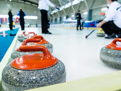 Kamienie do curlingu, każdy ważący ok. 20 kg, czekają na lodzie.